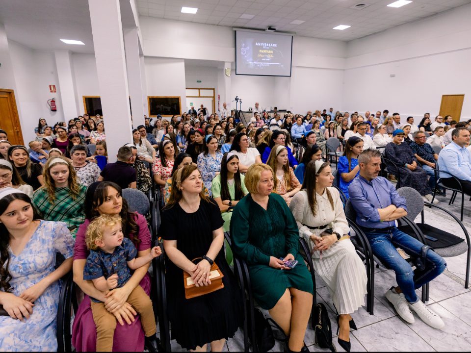Membri ai bisericii, de toate vârstele, așezați în sală în timpul unui serviciu.
